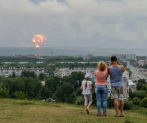 Una familia observa las explosiones en un depósito militar cerca de la ciudad de Achinsk, en la región de Krasnoyarsk, en el este de Siberia, Russia. Foto: AP