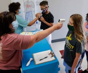 En esta fotografía de archivo del martes 14 de julio de 2020, en medio de los temores a la propagación de coronavirus, maestros revisan la temperatura a alumnos antes de un campamento de verano en la Secundaria Wylie en Wylie, Texas.