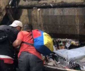 En las imágenes se ve a tres personas sacando comida del camión de la basura.