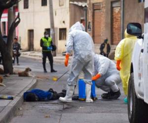 Trabajadores de salud con equipo para protegerse del coronavirus desinfectan el cadáver de un vendedor ambulante el sábado 25 de julio de 2020 en el vecindario Cerro San Miguel, en Cochabamba, Bolivia. Foto: AP