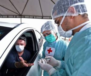 Los trabajadores de salud hacen una prueba rápida de COVID-19 a un hombre en un estacionamiento en el estacionamiento del estadio Mane Garrincha en Brasilia. Foto: Agencia AFP.