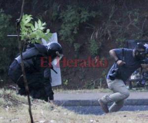 Emilio Flores, reportero de EL HERALDO, levanta sus brazos frente a los agentes policiales.