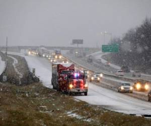 En medio de una ligera caída de nieve, una grúa arrastra un camión descompuesto para retirarlo de la interestatal 70 este en Lake St. Louis, Missouri. Foto AP