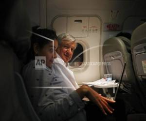 El presidente de México, Andrés Manuel López Obrador (centro), sentado junto a una asistente en un vuelo comercial en clase turista desde Guadalajara a la Ciudad de México.
