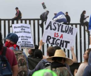 Unos 30 miembros de grupos pro-migrantes escalaron la valla fronteriza en donde gritaban “alerta, alerta, que camina la lucha del emigrante por América Latina”. (Foto: AFP)