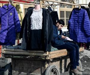 Un vendedor afgano que vende ropa de invierno se sienta en un carrito en un área de mercado en Kabul el 29 de diciembre de 2021. Foto: AFP