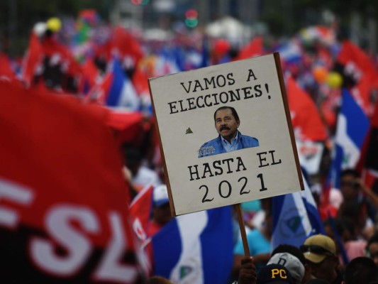 Un partidario del presidente nicaragüense Daniel Ortega sostiene un armario 'Vamos a las urnas. (Ortega) hasta 2021'. Agencia AFP.
