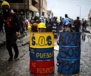 Manifestantes antigubernamentales se resguardan detrás de escudos de fabricación casera durante enfrentamientos con la policía en Bogotá. (AP Foto/Iván Valencia, Archivo).