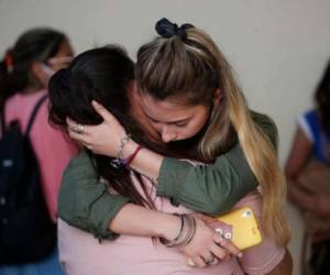Amigas de Úrsula Bahillo, de 18 años y que fue encontrada en un campo apuñalada hasta la muerte el lunes, se abrazan durante su velorio en Rojas, Argentina. Foto: AP