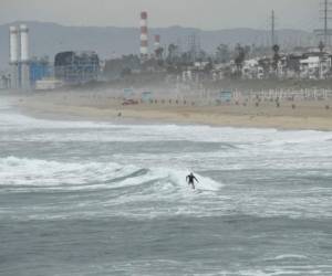 Un surfista atrapa una ola en Manhattan Beach, California, el 15 de enero de 2022. El Servicio Meteorológico Nacional de EE. UU. emitió avisos de tsunami para toda la costa oeste de los Estados Unidos luego de una erupción volcánica masiva en el Océano Pacífico en Tonga. Foto: AFP