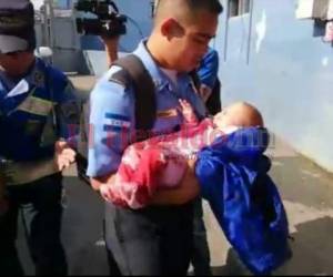 Una bebé de apenas meses es cargada por un elemento policial luego de resultar herida durante el accidente en carretera al sur del país. Foto: Estalin Irías/El Heraldo.