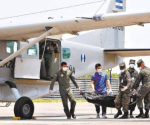 Efectivos de la Fuerza Aérea Hondureña bajan los cuerpos de una aeronave de la FAH.