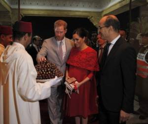 A su llegada, el príncipe Harry, en traje gris claro, y la duquesa de Sussex, con un vestido rojo, fueron recibidos con una tradicional bandeja de dátiles. Foto: AFP