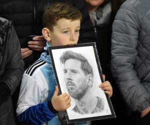 Un joven aficionado tiene una foto del delantero argentino Lionel Messi en la multitud antes del partido amistoso internacional. Foto: AFP