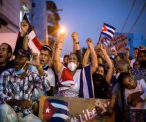 A man holds a placard that reads 'SOS Cuba Libertad' during a protest showing support for Cubans demonstrating against their government, at Versailles Restaurant in Miami, on July 18, 2021. - Cuba's President Miguel Diaz-Canel on July 17 denounced what he said was a false narrative over unrest on the Caribbean island, as the Communist regime vigorously pushed back against suggestions of historically widespread discontent. (Photo by Eva Marie UZCATEGUI / AFP)