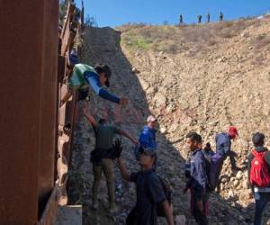 En esta foto de archivo tomada el 16 de diciembre de 2018, se ve a un grupo de migrantes centroamericanos que viajan en una caravana después de cruzar la valla fronteriza México-EE. UU. Al condado de San Diego, desde Tijuana, estado de Baja California, México.