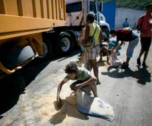 Algunos venezoanos recoge de la calle los granos que a los camiones se les cae. Foto: AP