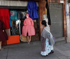 Una mujer aymara observa maniquíes en una tienda que vende ropa de protección adecuada para el estilo de vestir de las mujeres indígenas bolivianas en medio de la pandemia del nuevo coronavirus en La Paz, Bolivia, el miércoles 3 de junio de 2020.