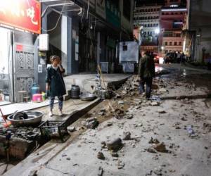 Una mujer se para fuera de un restaurante después de un terremoto de magnitud 5.0 en el condado de Qiaojia, ciudad de Zhaotong, en el sur de China. Foto AFP