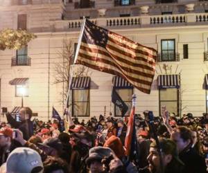 Los partidarios del presidente Donald Trump ondean una bandera de Betsy Ross con un círculo de 13 estrellas de cinco puntos que representan las 13 colonias originales durante una protesta el 12 de diciembre de 2020 en Washington, DC. Miles de manifestantes que se niegan a aceptar que el presidente electo Joe Biden ganó las elecciones se están reuniendo antes de la votación del colegio electoral para hacer oficial la derrota de Trump de 306 a 232. Foto: AFP