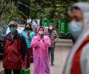 This photo taken on March 16, 2020 shows residents wearing face masks queueing to get their order of foods and vegetables in Wuhan, China's central Hubei province. - China reported on March 17 just one new domestic coronavirus infection but found 20 more cases imported from abroad, threatening to spoil its progress against the disease. (Photo by STR / AFP) / China OUT