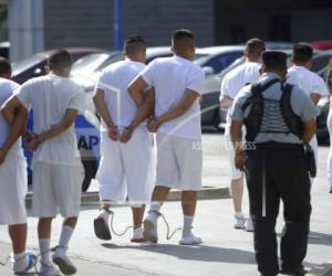 Un grupo de miembros de la pandilla Barrio 18, caminan en fila y con grilletes hacia el Centro de Justicia de San Salvador, el 2 de julio de 2018. El gobierno salvadoreño comenzó a tomar duras medidas contra las bandas hace 15 años, lo que resultó en la encarcelación de miles de sus miembros. (AP Foto/Salvador Melendez).