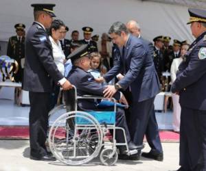 El presidente Juan Orlando saluda uno de los elementos de la Policía Nacional que asistió en silla de rueda al evento.