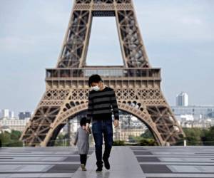Un hombre y su hijo con máscaras faciales caminan por la explanada vacía de Trocadero cerca de la Torre Eiffel en París. Foto: Agencia AFP.
