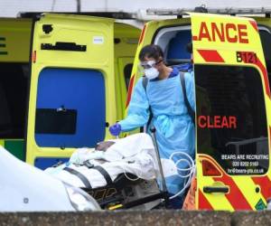 A medical professional in PPE, including gloves, eye protection and a face mask as a precautionary measure against Covid-19, carries a tank as a patient is taken from an ambulance into St Thomas' Hospital in north London, on April 1, 2020, as life in Britain continues during the nationwide lockdown to combat the novel coronavirus pandemic. - Britain reported 563 daily coronavirus deaths on Wednesday, the first time the national toll has exceeded 500, bringing the total fatalities to 2,352, according to official figures. 'As of 5pm (1600 GMT) on 31 March, of those hospitalised in the UK who tested positive for coronavirus, 2,352 have sadly died,' the health ministry said on its official Twitter page. (Photo by DANIEL LEAL-OLIVAS / AFP)