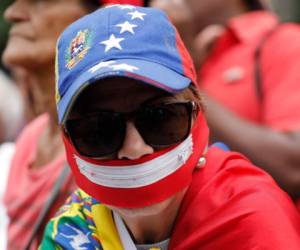 Una mujer que lleva una gorra con el motivo de una bandera nacional venezolana y una cremallera en la boca, espera la llegada del líder opositor y autoproclamado presidente interino de Venezuela, Juan Guaido, a Caracas, Venezuela, el martes 23 de julio de 2019.