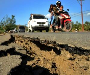 Un vehículo pasa junto a una carretera dañada en el subdistrito de Kayangan, en Lombok. Foto AFP