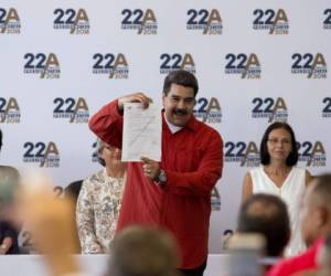 El presidente venezolano Nicolás Maduro presenta un certificado que formaliza su candidatura para las próximas elecciones presidenciales en el Consejo Nacional Electoral (CNE) en Caracas, Venezuela. Foto AFP