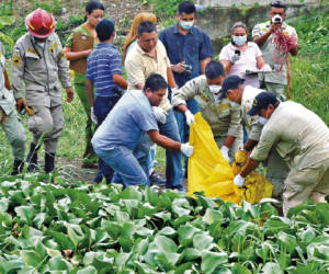 Firefighters remove a body found in a field on the outskirts of San Pedro Sula, Honduras, Tuesday, July 10, 2011. Honduran authorities have confirmed that the charred and mutilated body found here is that of missing journalist Anibal Barrow. The 62-year-old journalist had a popular daily morning news show called 'Anibal and Nothing More' on Globo television in San Pedro Sula. Heavily armed men kidnapped Barrow on June 24. (AP Photo)