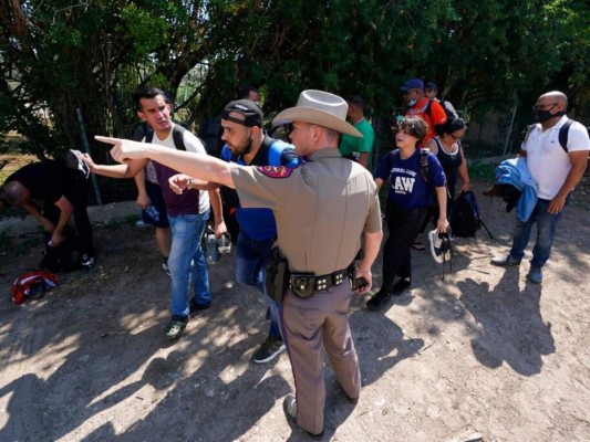En esta fotografía de archivo del miércoles 16 de junio de 2021, un agente del Departamento de Seguridad Pública en Del Rio, Texas, dirige hacia un lugar a un grupo de migrantes que cruzaron la frontera y se entregaron a las autoridades. Foto: AP