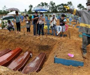 Los dolientes se paran junto a una fosa común en el cementerio Nossa Senhora en Manaos, estado amazónico, Brasil, el 6 de mayo de 2020, en medio de la pandemia de coronavirus Covid-19. Foto: Agencia AFP.