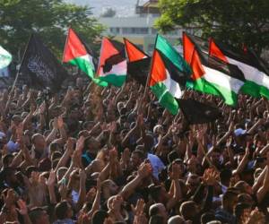 Dolientes palestinos gritan consignas mientras ondean banderas palestinas durante el funeral de Mohammad Kiwan, de 17 años, cuya familia asegura que murió en enfrentamientos con policías israelíes. Foto: AP