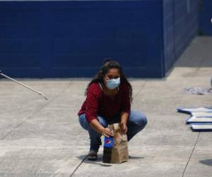 Vanessa Díaz, quien fue deportada por EEUU, recoge la comida que su madre le lleva al sitio donde los migrantes que regresan deben pasar dos semanas en cuarentena. Ya de vuelta en su casa, Díaz tiene miedo de ser agredida por vecinos. Foto: AP.