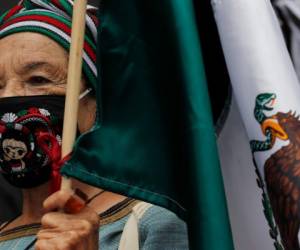 Una mujer con mascarilla para frenar la propagación del nuevo coronavirus, sostiene una bandera mexicana en una de las principales avenidas del centro de la Ciudad de México, el domingo 13 de septiembre de 2020.