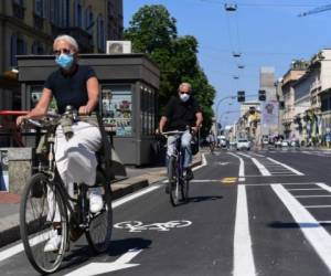 Las personas andan en bicicleta a través de un carril bici en el centro de Milán el 4 de mayo de 2020, cuando Italia comienza a aliviar su bloqueo, durante el bloqueo del país destinado a frenar la propagación de la infección por COVID-19, causada por el nuevo coronavirus. Foto: Agencia AFP.