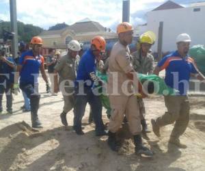 Personal del Cuerpo de Bomberos mientras traslada uno de los cadáveres de las víctimas que murieron soterradas en construcción de la colonia América, al sur de la capital. Fotos: Wilfredo Alvarado/ Estalin Irias/ EL HERALDO.