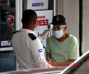 Los termómetros pistolas son usados en Honduras por anfitriones de los establecimientos para medir la temperatura corporal de cada cliente que ingresa. Foto: EL HERALDO.