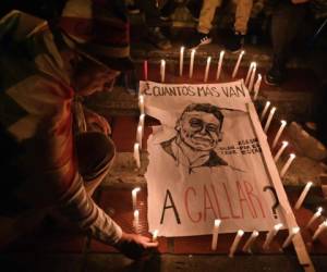 Un hombre enciende una vela alrededor de un cartel que dice '¿Cuántos más vas a callar?' y representando a Dilan Cruz, una joven manifestante que había sido herida por un miembro del Escuadrón Antidisturbios Móvil (ESMAD) durante una protesta contra el gobierno colombiano. Foto: AFP.