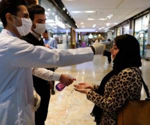 Una mujer se somete a un control de temperatura mientras se desinfecta las manos al entrar al centro comercial Palladium, en Teherán, Irán, el 3 de marzo de 2020. AP
