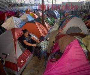 Ruth Aracely Monroy ayuda a su hijo Carlos a ponerse una chaqueta en un refugio donde migrantes viven en carpas en Tijuana, México, el 5 de marzo del 2019. (AP Photo/Gregory Bull)