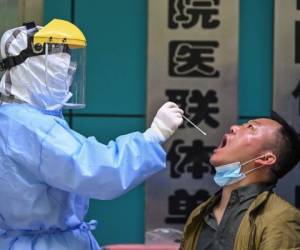 Un trabajador médico toma una muestra de un hisopo de un hombre sometido a pruebas de detección del nuevo coronavirus COVID-19 en Wuhan. Foto: Agencia AFP.