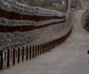 Un niño anda en bicicleta junto al muro cubierto de alambre de púas que separa a Nogales, Arizona, de Nogales, México, al otro lado, el sábado 2 de marzo de 2019. (AP Foto/Charlie Riedel)