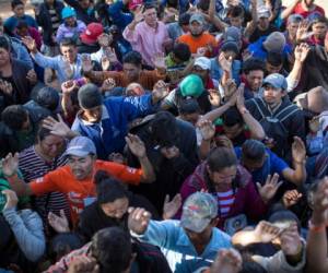 Miembros de la caravana migrante realizando una oración a su llegada a la frontera con Estados Unidos. Foto AP/ El Heraldo Honduras.