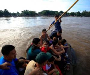 Más de una docena de migrantes hondureños viaja en balsa a través del río Suchiate, ubicado entre Tecun Uman, Guatemala, y ​​Ciudad Hidalgo en México, algunos operadores de negocios de la ribera dijeron que el flujo de migrantes a través del cruce ha disminuido desde el anuncio hace unos días de que la nueva Guardia Nacional de México se desplegaría en la frontera. Foto: Cortesía AP / Rebecca Blackwell.