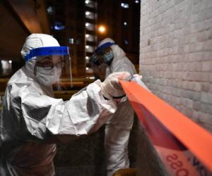 Los agentes de policía con trajes protectores instalaron un cordón en los terrenos de una urbanización en Hong Kong, después de que se confirmó que una familia habían contraído el coronavirus según informes de periódicos locales. Fotos: AFP.