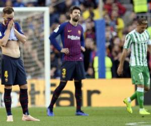 Ivan Rakitic se tapa el rostro mientras Piqué no puede creer que Joaquín haya anotado el 2-0 del Betis sobre el Barcelona en el Camp Nou. (AFP)